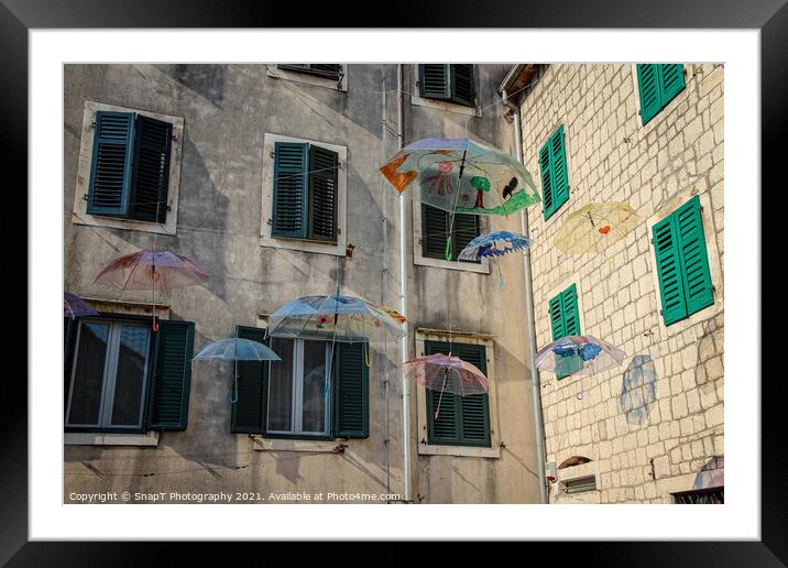 Flying umbrellas in a square in the old town of Kotor, in Montenegro Framed Mounted Print by SnapT Photography