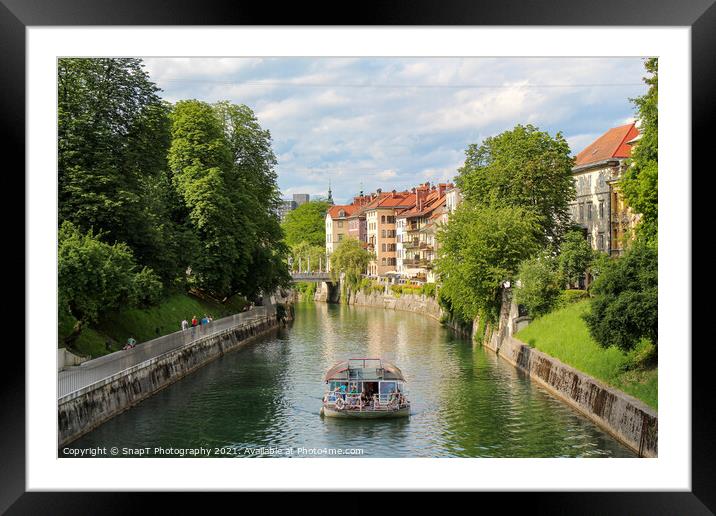A tourist boat travelling along the Ljublijanica River in afternoon in Ljubljana Framed Mounted Print by SnapT Photography
