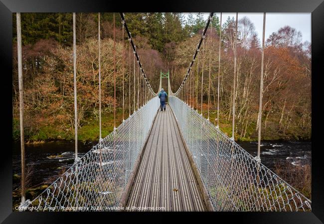 Man walking over an old wooden suspension bridge across a river in Scotland Framed Print by SnapT Photography