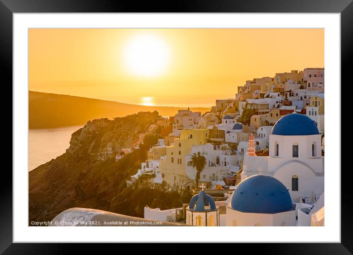 Blue domed churches and traditional white houses facing Aegean Sea with warm sunset light in Oia, Santorini, Greece Framed Mounted Print by Chun Ju Wu