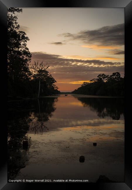A sunset over a body of water Framed Print by Roger Worrall