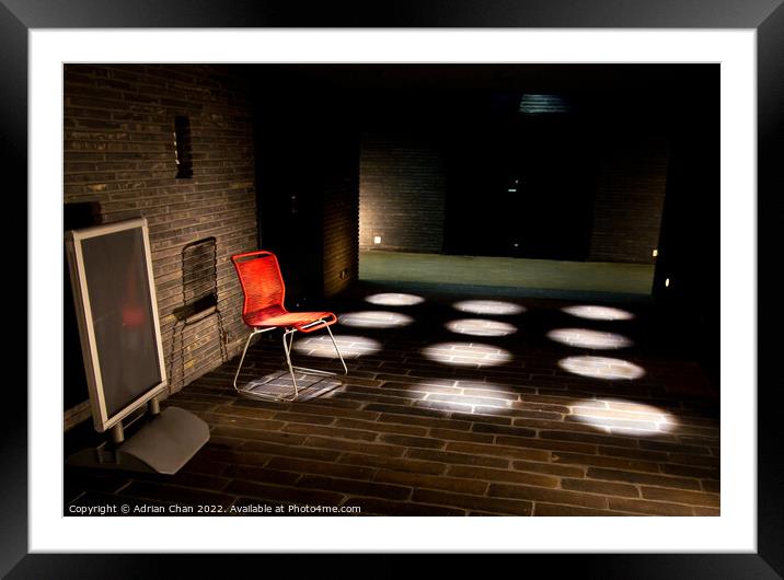 A lone red chair in the spotlight Framed Mounted Print by Adrian Chan
