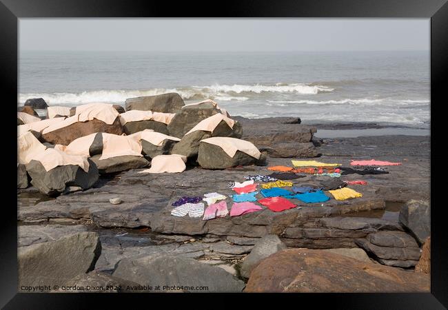 Freshly laundered clothes and fabrics drying on rocks by the sea at Mumbai, India Framed Print by Gordon Dixon