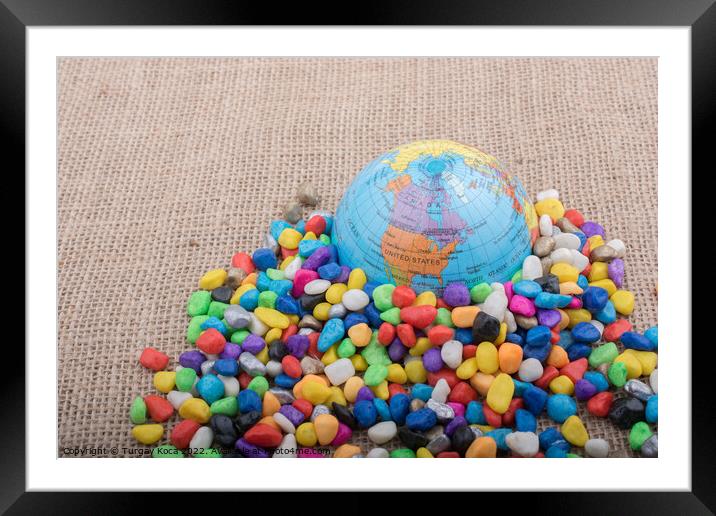 Little model globe amid colorful pebbles  Framed Mounted Print by Turgay Koca