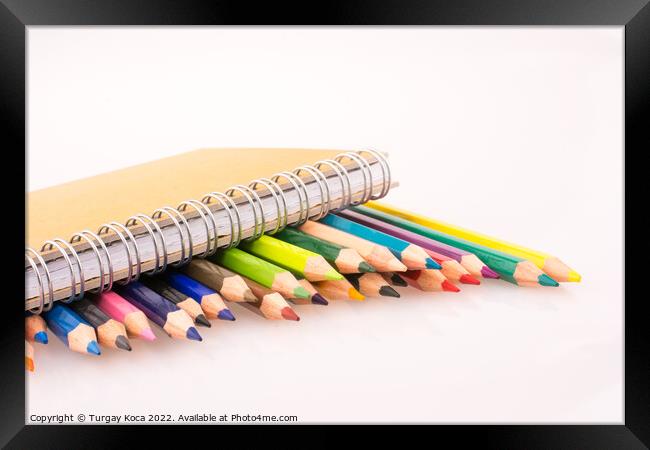 color pencils of various colors near a notebook Framed Print by Turgay Koca