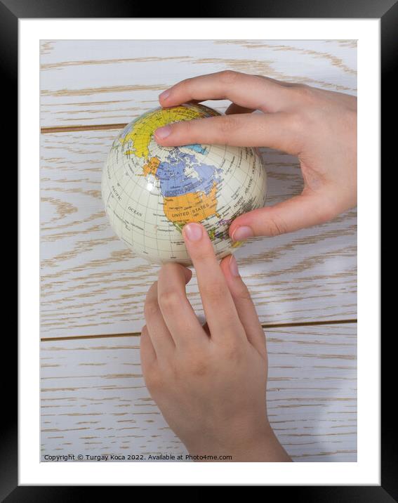 Hand holding a globe  with the map on it Framed Mounted Print by Turgay Koca