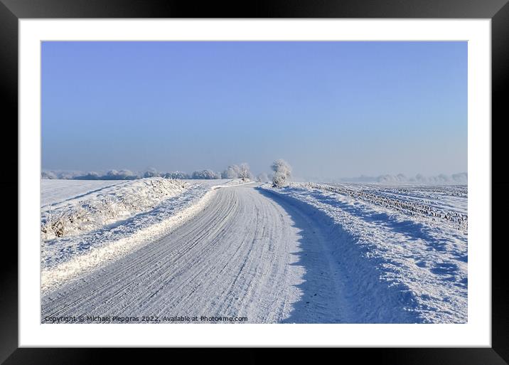 View of a snow-covered country road in winter with sunshine and  Framed Mounted Print by Michael Piepgras