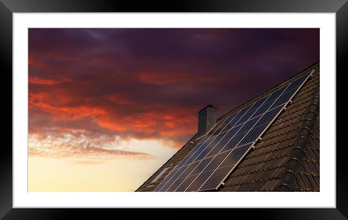 Solar panels producing clean energy on a roof of a residential house during sunset. Framed Mounted Print by Michael Piepgras
