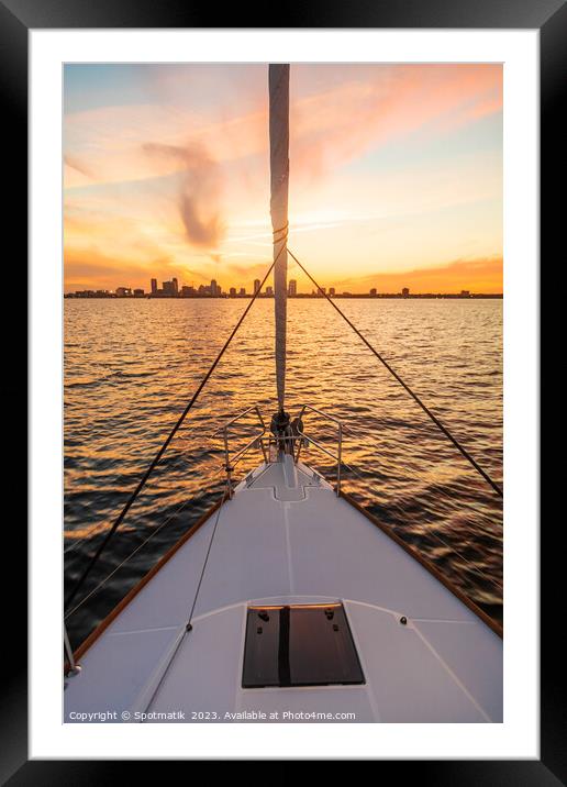 Bow of yacht sailing towards cityscape at sunrise Framed Mounted Print by Spotmatik 