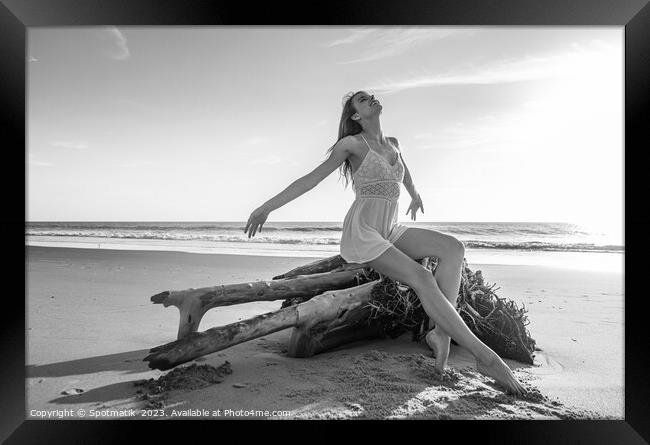 Young beach girl enjoying sun sitting on driftwood  Framed Print by Spotmatik 