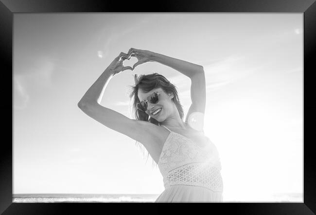 Bohemian girl showing heart sign dancing on beach Framed Print by Spotmatik 