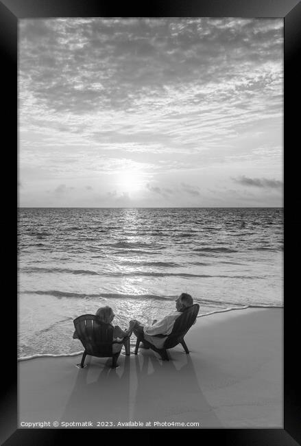Sunset view with retired couple relaxing by ocean Framed Print by Spotmatik 