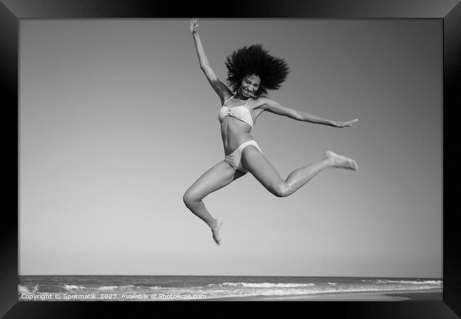 Fun loving Afro female jumping by the ocean Framed Print by Spotmatik 