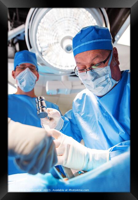 Medical surgeon operating on patient under overhead light Framed Print by Spotmatik 