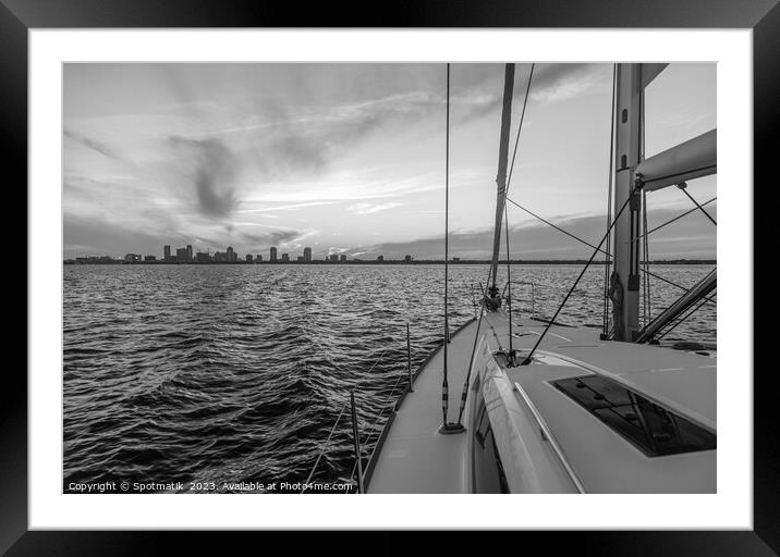 Yacht sailing towards cityscape on horizon at sunset Framed Mounted Print by Spotmatik 