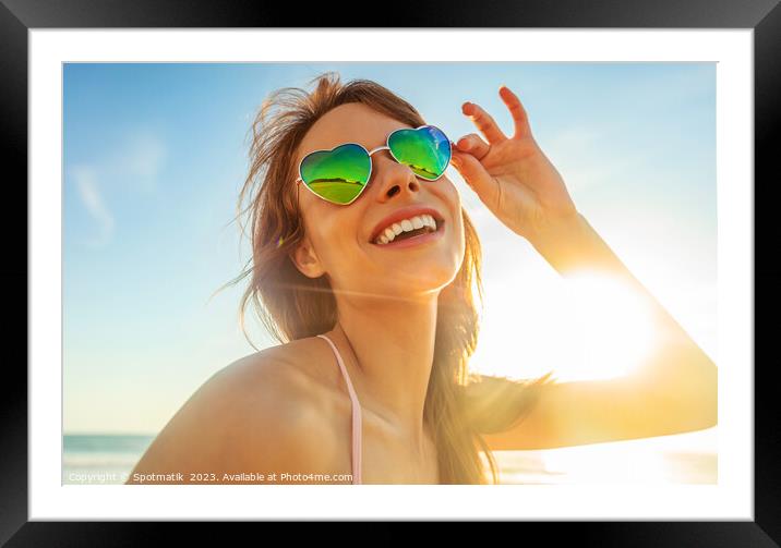 Caucasian girl wearing heart shaped sunglasses on beach Framed Mounted Print by Spotmatik 