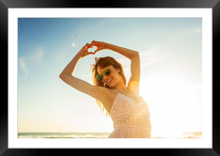 Bohemian girl showing heart sign dancing on beach Framed Mounted Print by Spotmatik 