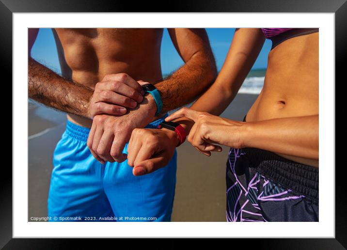Fit young couple on beach setting activity trackers Framed Mounted Print by Spotmatik 