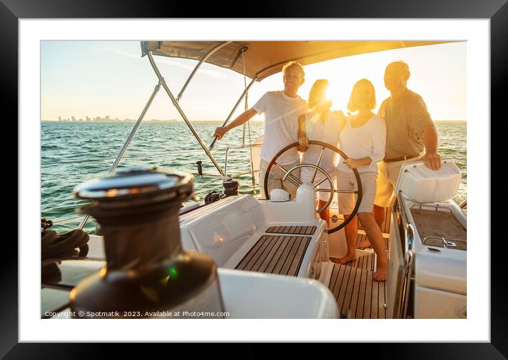 Senior friends enjoying retirement steering yacht at sunset Framed Mounted Print by Spotmatik 