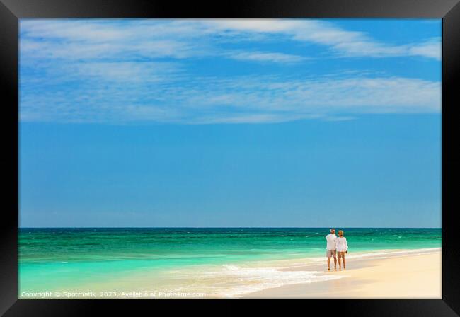 Retired couple walking barefoot by turquoise ocean Bahamas Framed Print by Spotmatik 