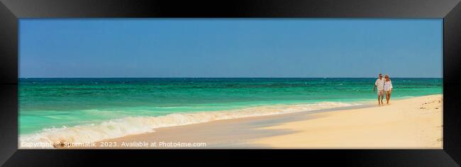 Panoramic view mature couple walking on deserted beach Framed Print by Spotmatik 