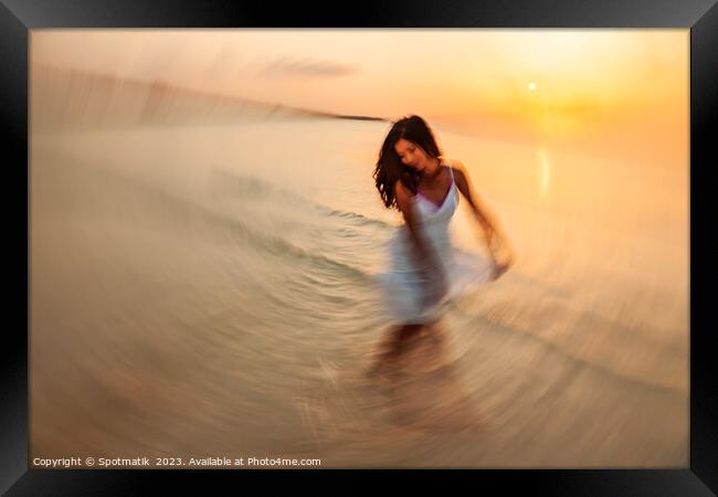 Motion blurred dancing Asian girl in ocean sunset Framed Print by Spotmatik 