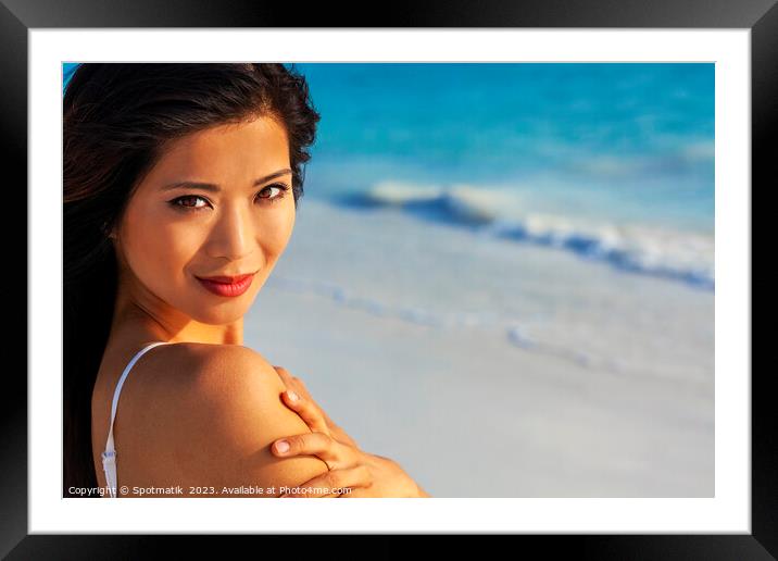 Portrait of smiling Asian woman by ocean waves Framed Mounted Print by Spotmatik 