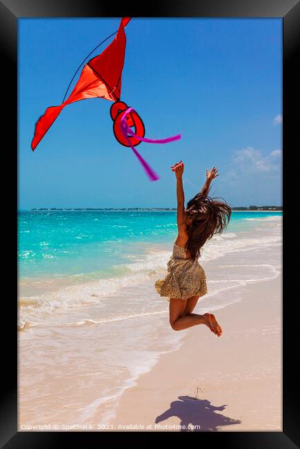 Happy Asian girl jumping by ocean flying kite Framed Print by Spotmatik 