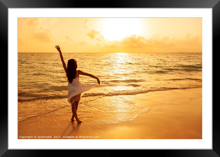 Asian girl standing in ocean waves at sunrise Framed Mounted Print by Spotmatik 