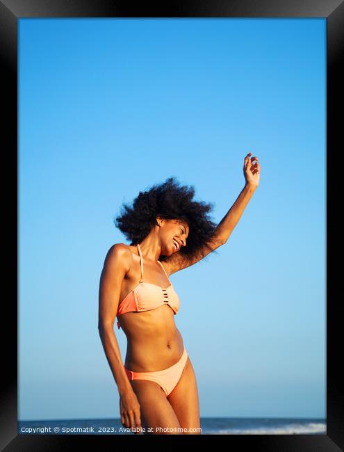 Afro girl in swimwear dancing on the beach Framed Print by Spotmatik 