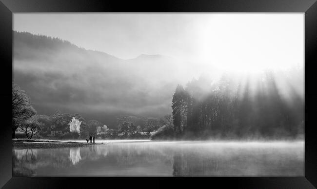 Family playing on shores of Derwent Water on a cold winters morning with mist and sun beams Framed Print by Julian Carnell