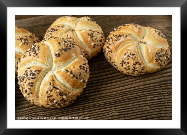 Whole wheat bread on wooden background. Bunch of kaiser rolls with sesame. Framed Mounted Print by Lubos Chlubny