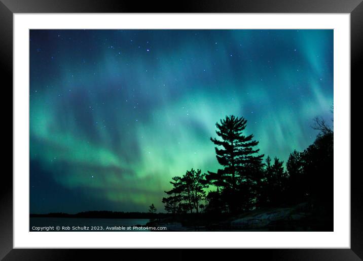 Northern lights erupt over a lake in Minnesota in a dark sky ove Framed Mounted Print by Rob Schultz