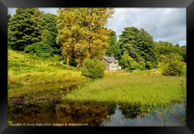 Romantic cottage in trees with water reflecting light  Framed Print by Jonny Angle