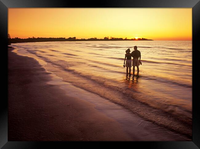 couple along beach at sunset Framed Print by Dave Reede