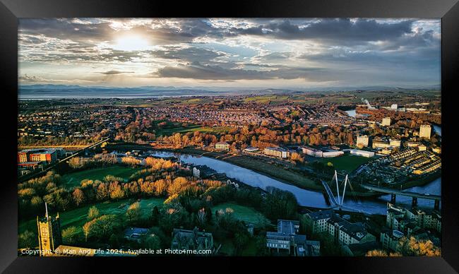 Aerial view of Lancaster city at sunset with a river flowing through, highlighting the urban landscape and green spaces under a dramatic sky. Framed Print by Man And Life