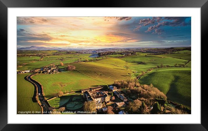 Aerial view of a picturesque rural landscape at sunset with vibrant green fields, a small village, and a winding road. Framed Mounted Print by Man And Life