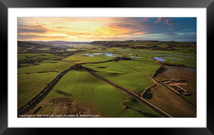 Aerial view of a lush green countryside at sunset with rolling hills, fields, and a winding river. Framed Mounted Print by Man And Life