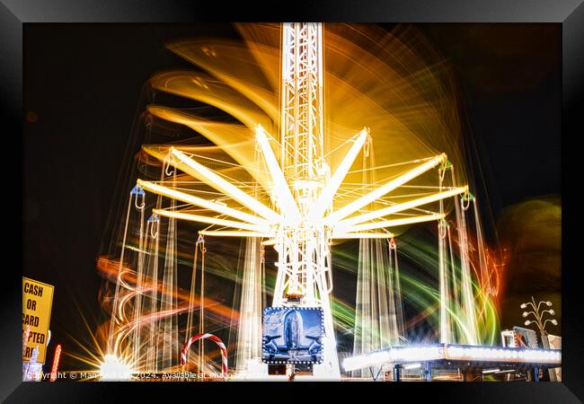 Long exposure of a brightly lit carousel at night, capturing motion blur of spinning lights at a fair. Framed Print by Man And Life