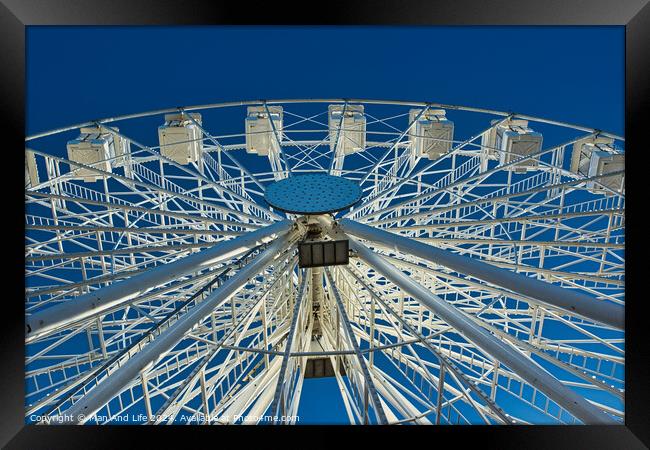Ferris wheel against a clear blue sky, symmetrical view from below in Lancaster. Framed Print by Man And Life