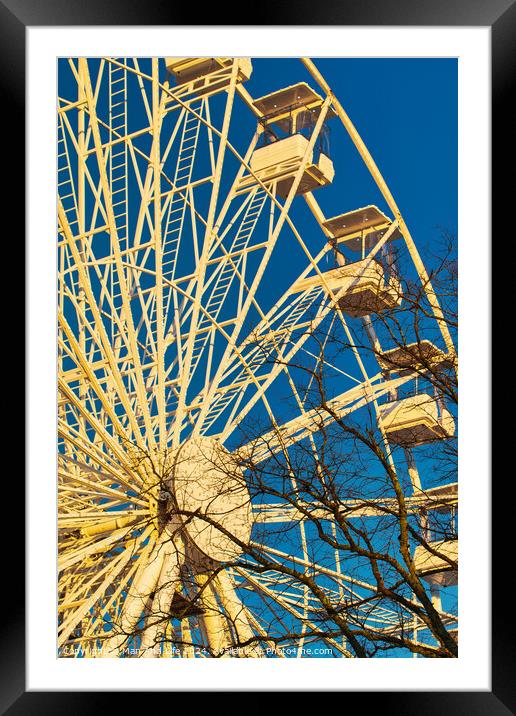 Ferris wheel against a clear blue sky with sunlight casting shadows, conveying a sense of leisure and entertainment in Lancaster. Framed Mounted Print by Man And Life