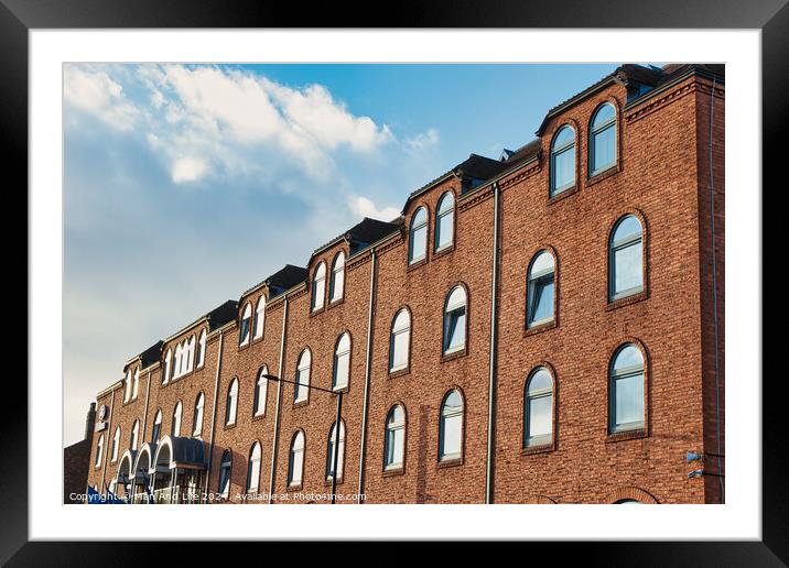 Row of traditional brick buildings against a blue sky with clouds in York, UK. Framed Mounted Print by Man And Life