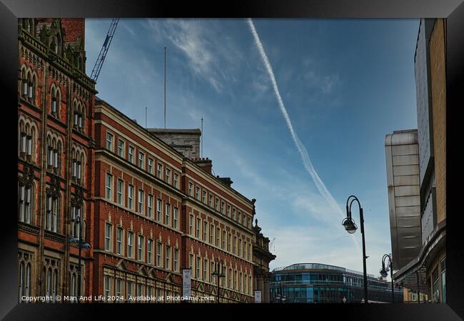 Urban street view with historic buildings under a clear blue sky with contrails in Leeds, UK. Framed Print by Man And Life