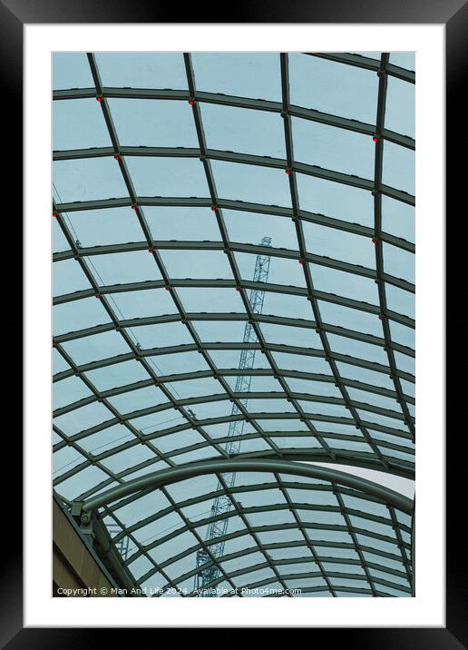 Abstract view of a glass ceiling with a metal frame, showcasing geometric patterns and a clear blue sky in the background. Framed Mounted Print by Man And Life