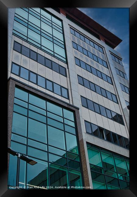 Modern office building facade with reflective glass windows against a blue sky in Leeds, UK. Framed Print by Man And Life