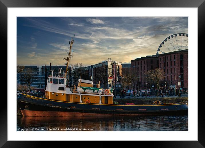 Tugboat in city harbor at sunset with ferris wheel and buildings in background in Liverpool, UK. Framed Mounted Print by Man And Life