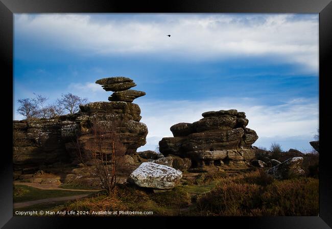 Scenic view of unique rock formations under a blue sky with a solitary bird flying overhead at Brimham Rocks, in North Yorkshire Framed Print by Man And Life
