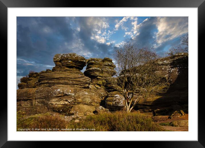 Dramatic landscape with weathered rock formations and a solitary tree under a cloudy sky at Brimham Rocks, in North Yorkshire Framed Mounted Print by Man And Life