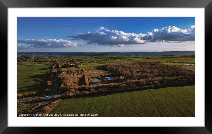 Aerial view of lush green fields with a small forest area, under a vast blue sky with fluffy clouds in North Yorkshire. Framed Mounted Print by Man And Life