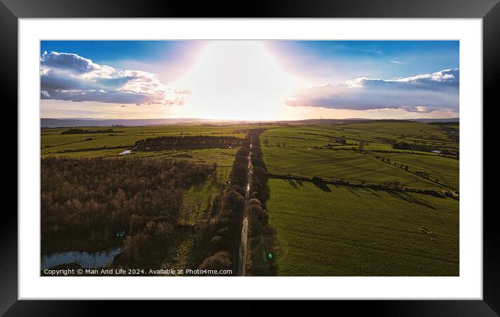 Aerial view of a scenic country road at sunset with lush green fields and a dramatic sky in North Yorkshire. Framed Mounted Print by Man And Life